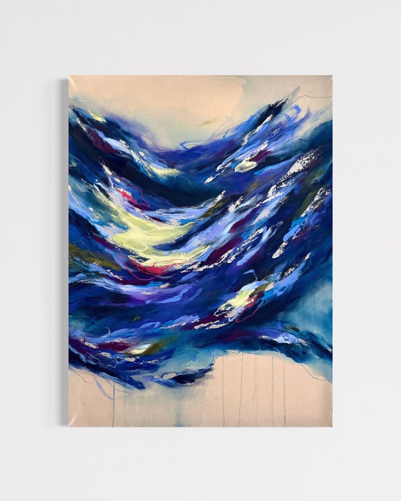 An abstract canvas painting featuring dynamic, textured brushstrokes of deep blue, navy, and white, accented with splashes of yellow, red, and purple, set against a light beige background. The painting is shown hanging on a neutral light gray wall.